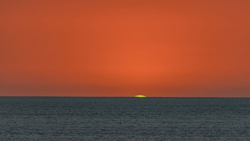 Why exists in some cases a green flash at sundown and daybreak?